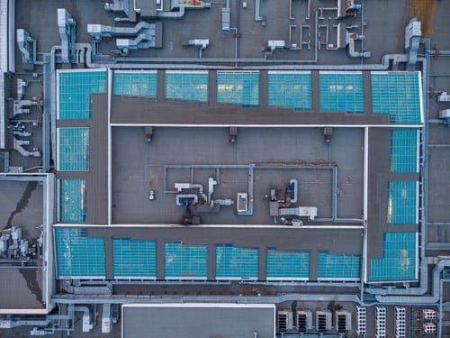 Aerial view of a large commercial flat roof with skylights, drains and rooftop equipment prepared for a waterproofing system