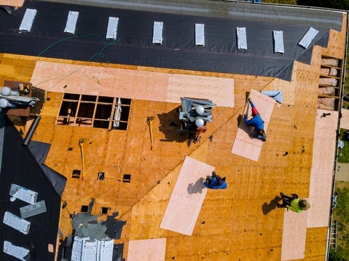 1st Rate Roofing crew applying a reflective roof coating system on a Gulf Coast building